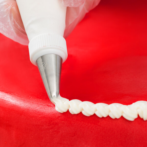 A person using an Ateco leaf piping tip on a pastry bag to decorate a cake.