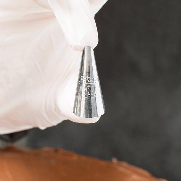 A hand holding an Ateco ruffle piping tip.