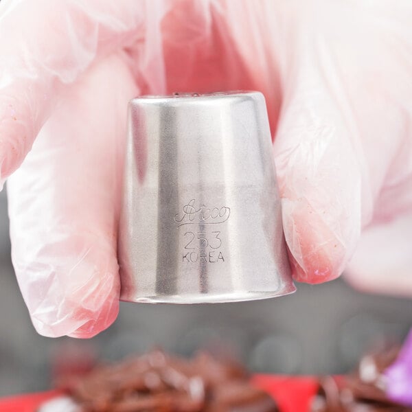 A person using an Ateco Russian piping tip to pipe frosting onto a dessert.