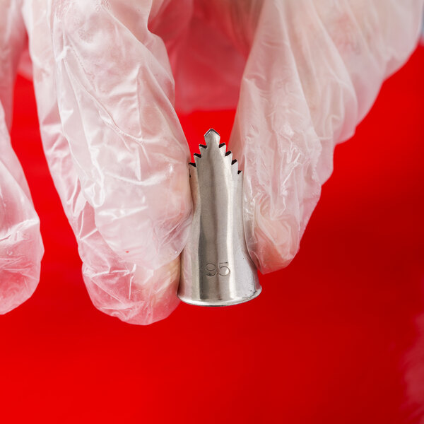 A hand holding an Ateco metal leaf piping tip.