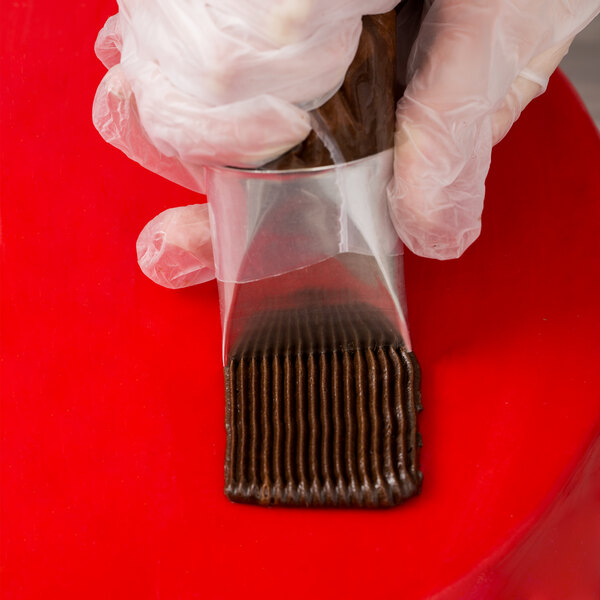 A person in gloves holding a plastic bag of chocolate.