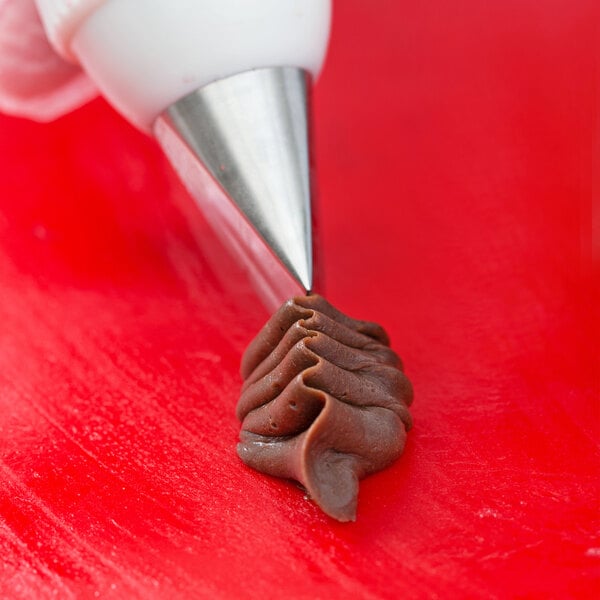 A pastry bag with an Ateco rose leaf piping tip and brown frosting.
