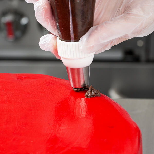 A person using an Ateco Christmas tree piping tip to decorate a cake.