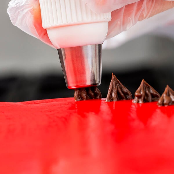 A person using an Ateco Christmas tree piping tip on a red surface.
