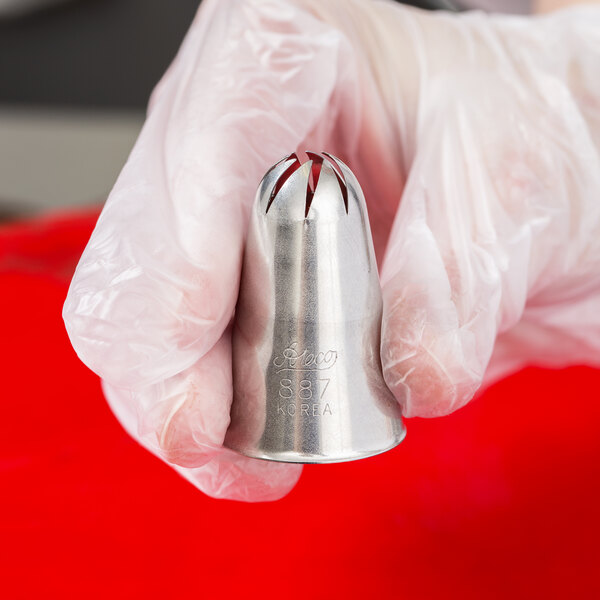 A hand holding a silver Ateco Swirl Top Piping Tip.