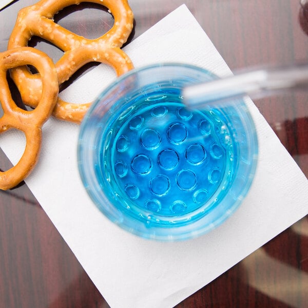 A Libbey Nob Hill rocks glass filled with blue liquid next to a pretzel on a napkin.