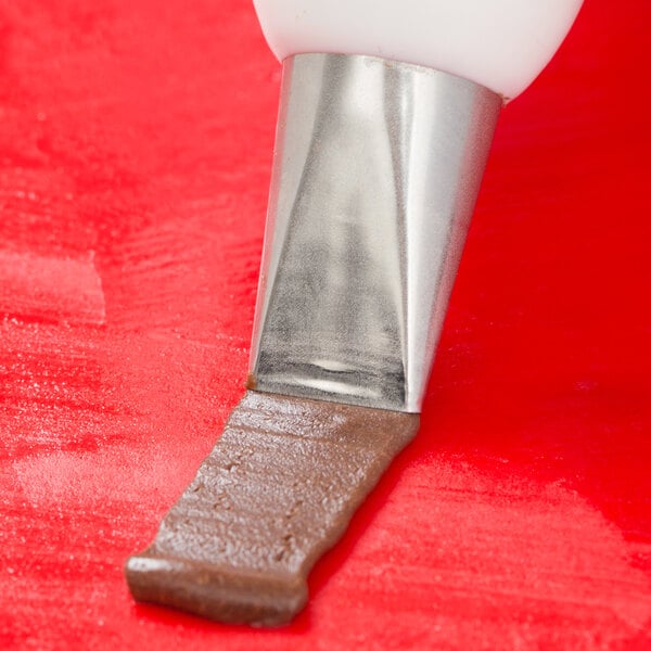 A person using an Ateco basketweave piping tip to pipe chocolate.