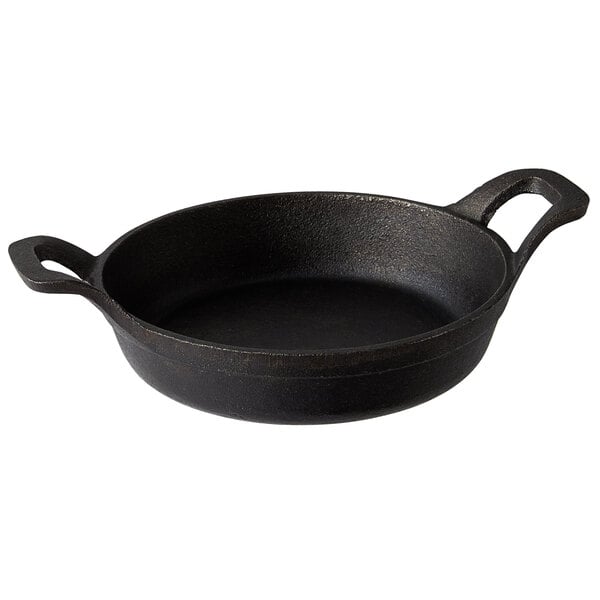 A black cast iron mini round casserole dish with handles.