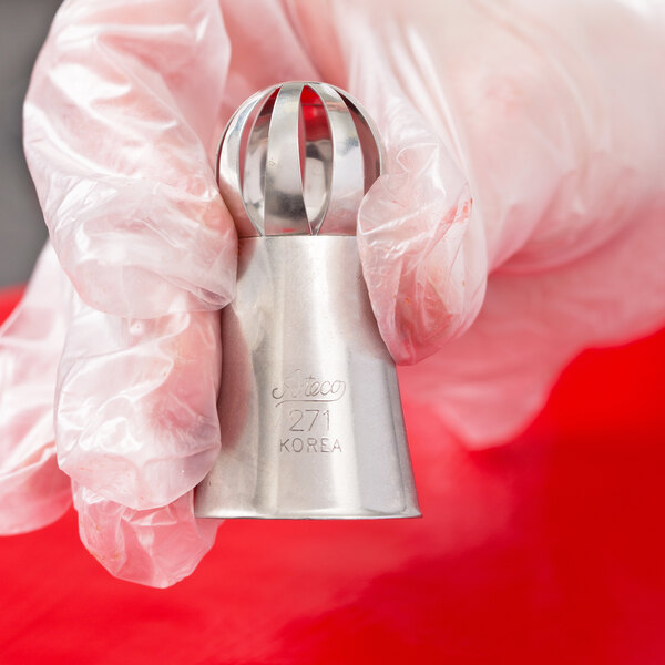 A person using an Ateco Russian ball tip piping tip to decorate pastries on a counter.