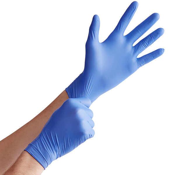 A pair of blue nitrile exam gloves being worn on hands.
