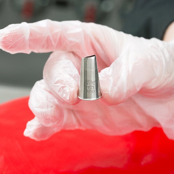 A hand in white gloves holding an Ateco curved petal metal piping tip.