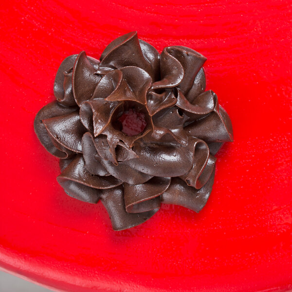 A chocolate swirl piped with an Ateco Russian ball tip on a red surface.