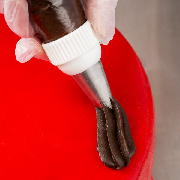 A person using an Ateco swirl top piping tip on a pastry bag to decorate a cake.