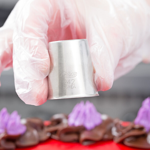 A hand holding a cupcake with piped frosting using an Ateco Russian piping tip.