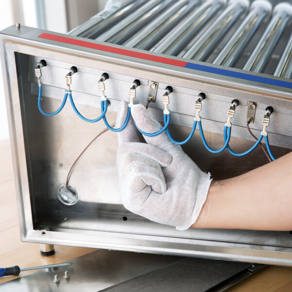 A person's hand in a Cordova inspection glove holding a machine.