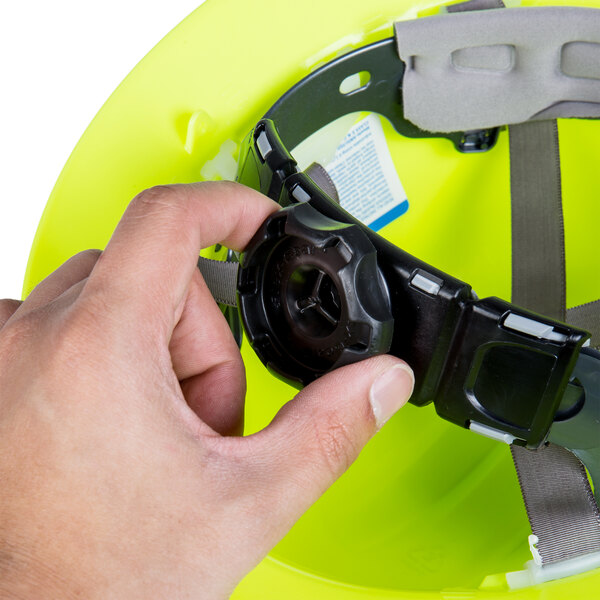 A person holding a Cordova Hi-Vis green hard hat with black suspension straps.