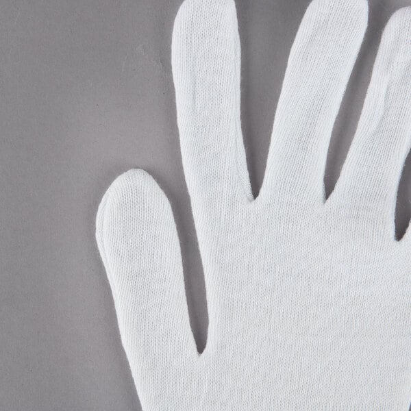 A Cordova white inspection glove on a gray surface.