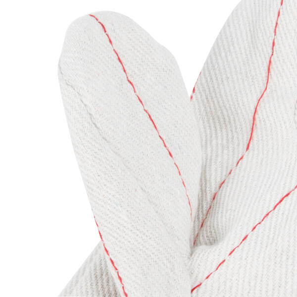 A close up of a Cordova white cotton work glove with red stitching.