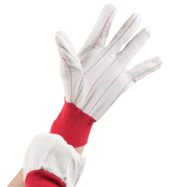 A hand wearing white gloves with red stripes.