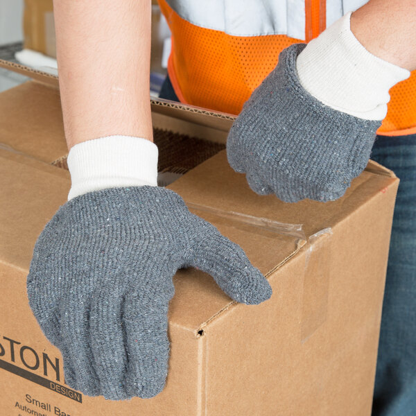 A person wearing Cordova loop-out gray jersey gloves and holding a box.