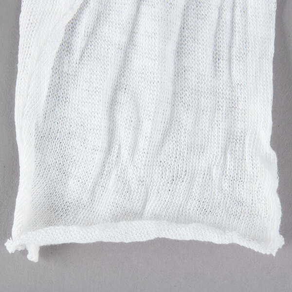 A pair of white Cordova cotton gloves on a gray surface.