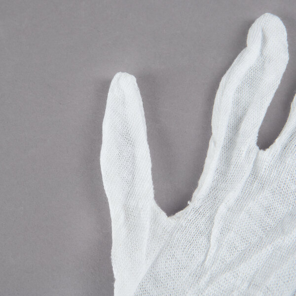 A Cordova white cotton glove on a gray surface.