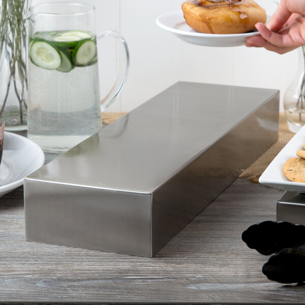 A Tablecraft stainless steel rectangular bowl on a table with food in it.
