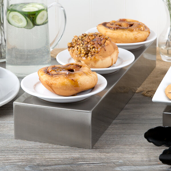 A Tablecraft stainless steel rectangular bowl filled with pastries on a table in a bakery display.