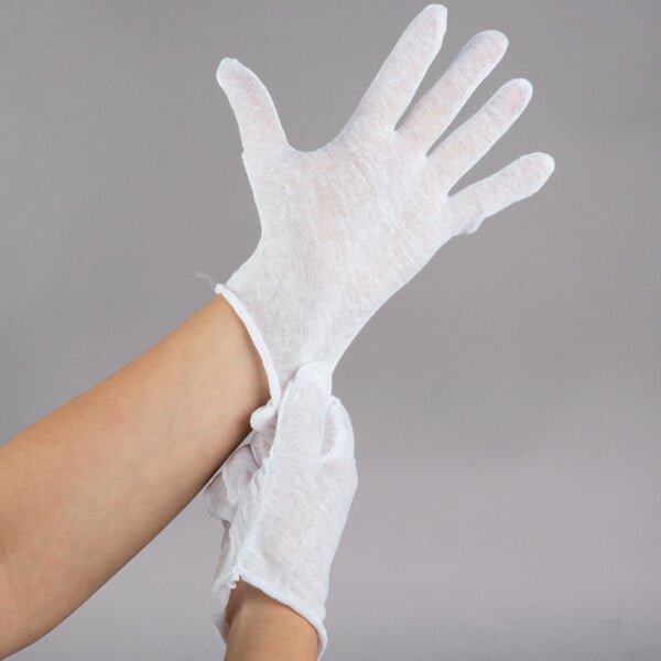 A person's hand wearing white Cordova inspection gloves.