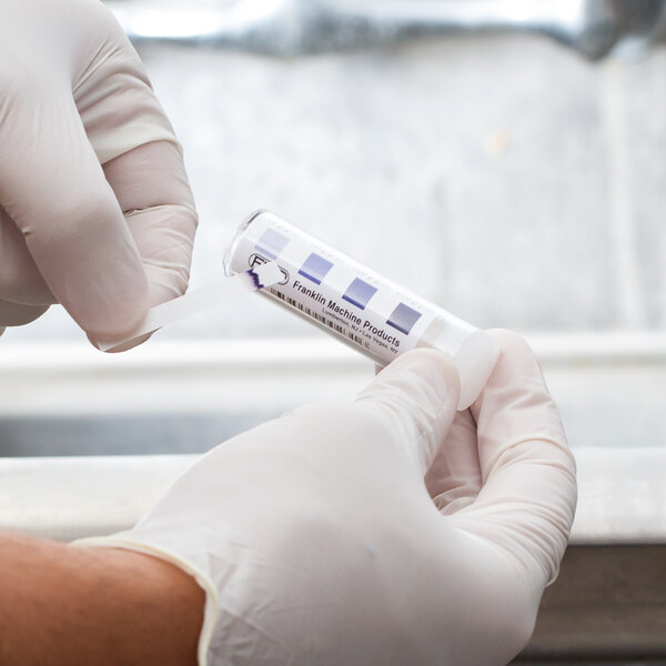 A person in white gloves using FMP Chrome Chlorine Sanitizer Test Strips.