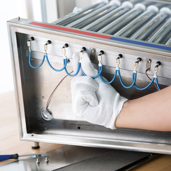 A person's gloved hand holding blue wires.
