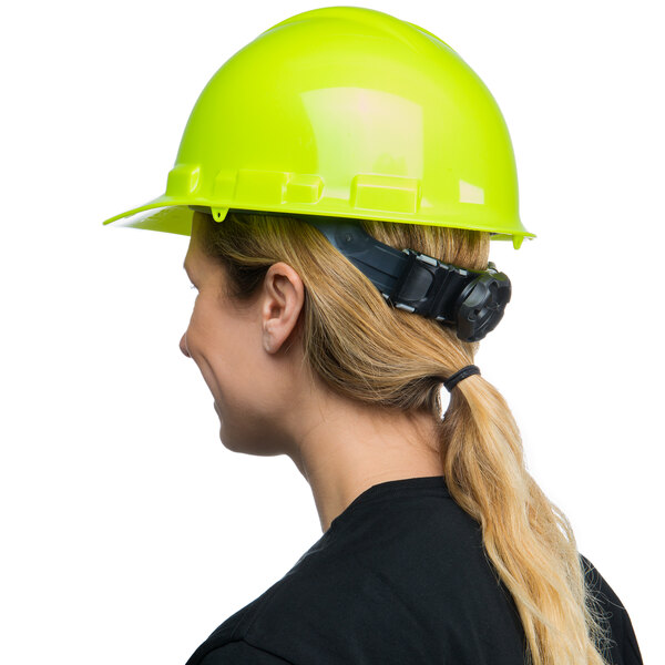 A woman wearing a green Cordova cap style hard hat with a ratchet suspension.