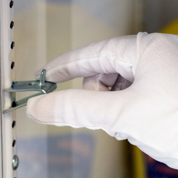 A hand in a white Cordova inspector's glove holding a metal tool.