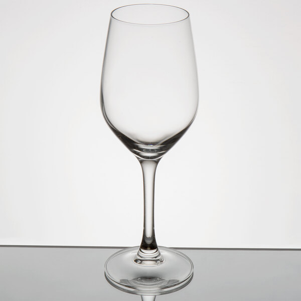 An empty Arcoroc wine glass on a reflective surface.