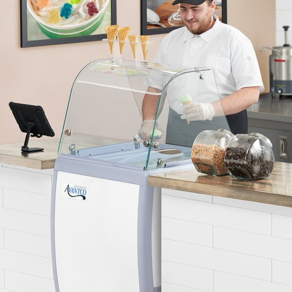 An Avantco curved glass sneeze guard on a counter in an ice cream shop.