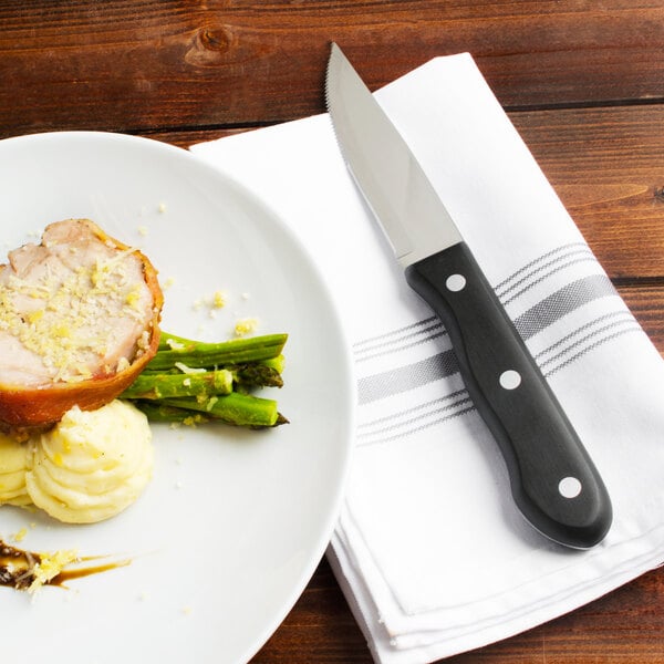 A plate of food with a Walco steak knife and fork on a table.