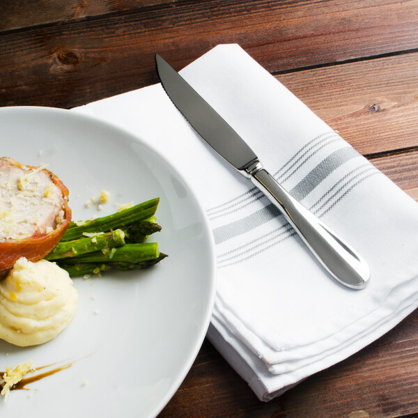 A plate of food with a Walco Lancer steak knife and fork on a napkin.