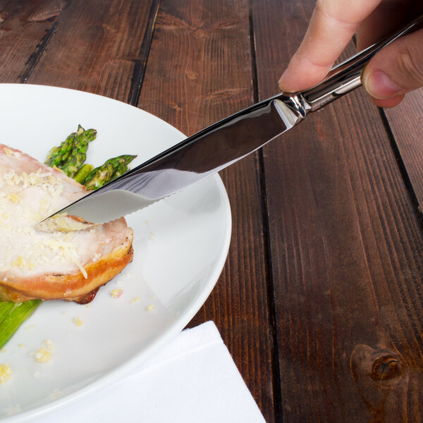 A person cutting food on a plate with a Walco Lancer steak knife.
