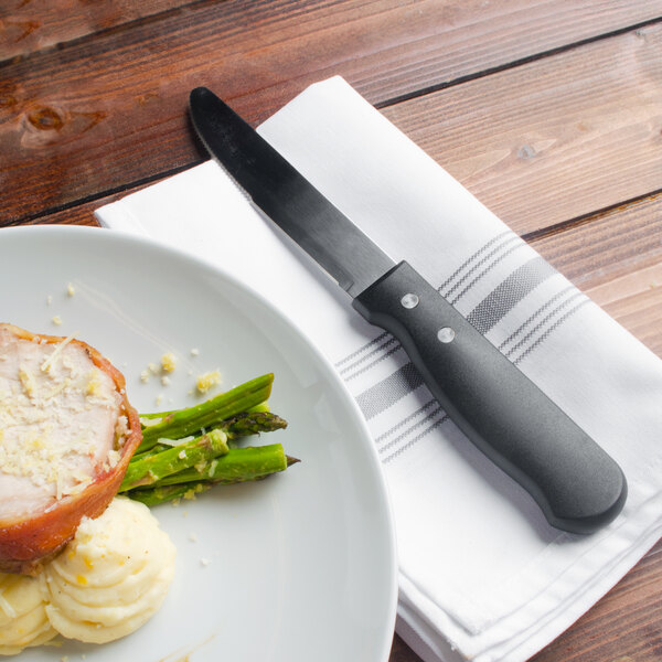 A plate of food with a Walco stainless steel steak knife on a napkin.