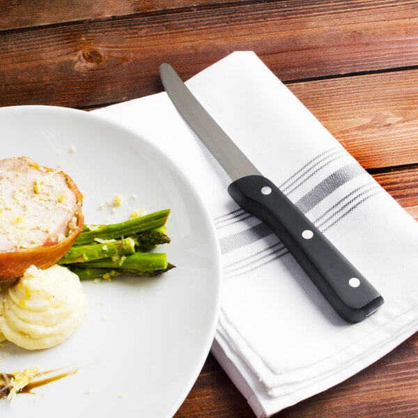 A Walco steak knife on a white plate with food