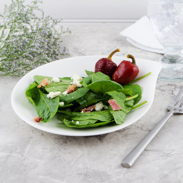 A Villeroy & Boch white porcelain plate with a spinach salad topped with bacon, red onion, and feta cheese on a table with a fork.