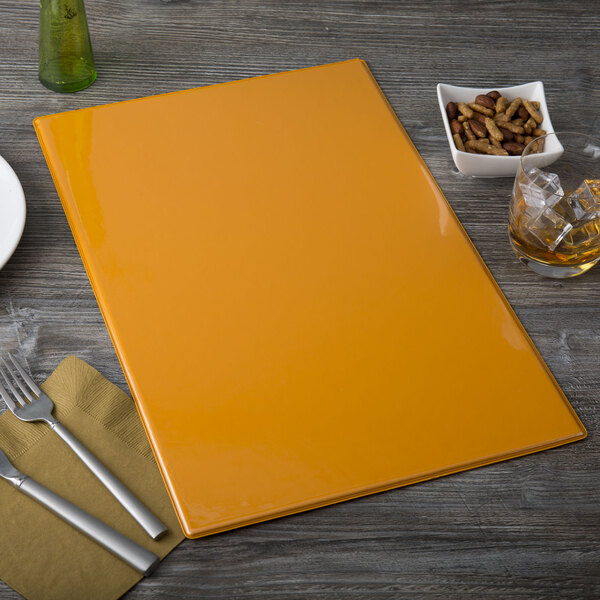 A yellow rectangular Menu Solutions Hamilton Mandarin menu board on a table with a glass of green liquid and ice.