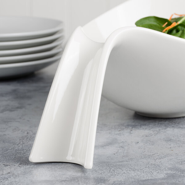 A white Villeroy & Boch porcelain bowl with a curved edge filled with salad.