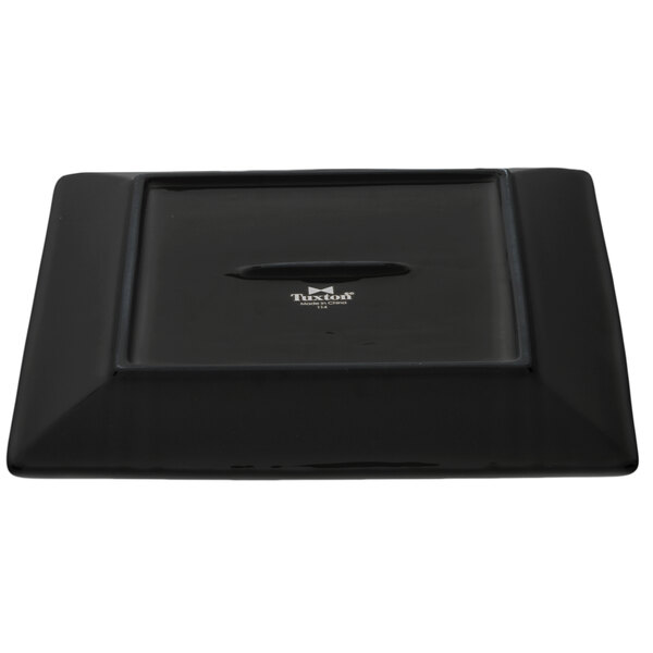 A black square Tuxton china plate with a logo on it.