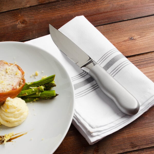 A plate of food with a Walco steak knife on a napkin.