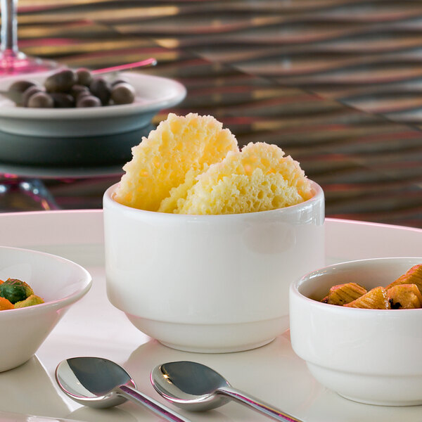 A white plate topped with a Villeroy & Boch white dip bowl filled with food.