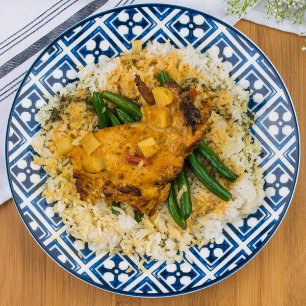 An Arcoroc Candour Azure porcelain brunch plate with a plate of chicken, rice, and green beans on a wood surface.