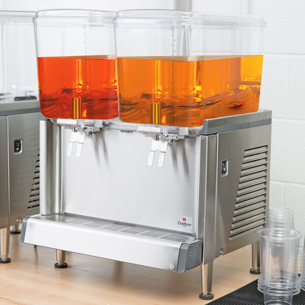 A Crathco double beverage dispenser with orange and blue drinks.