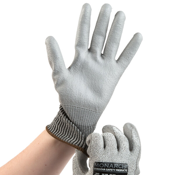 A close-up of a hand wearing a gray and white Cordova Monarch work glove.