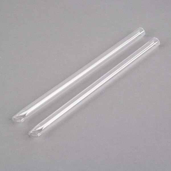 A clear tube with a clear wrapper next to another clear tube on a gray surface.